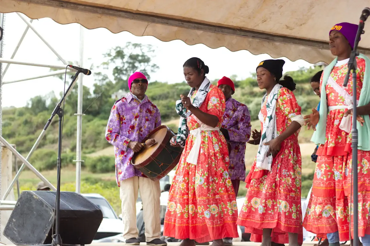Des chanteuses et des percussionnistes en tenue traditionnelle sur une scène en plein air